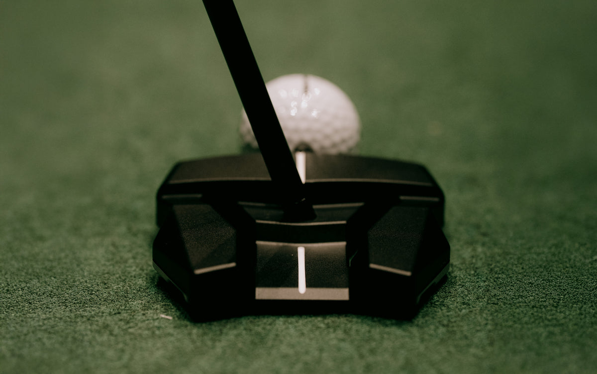 Golf putter and ball on a green surface