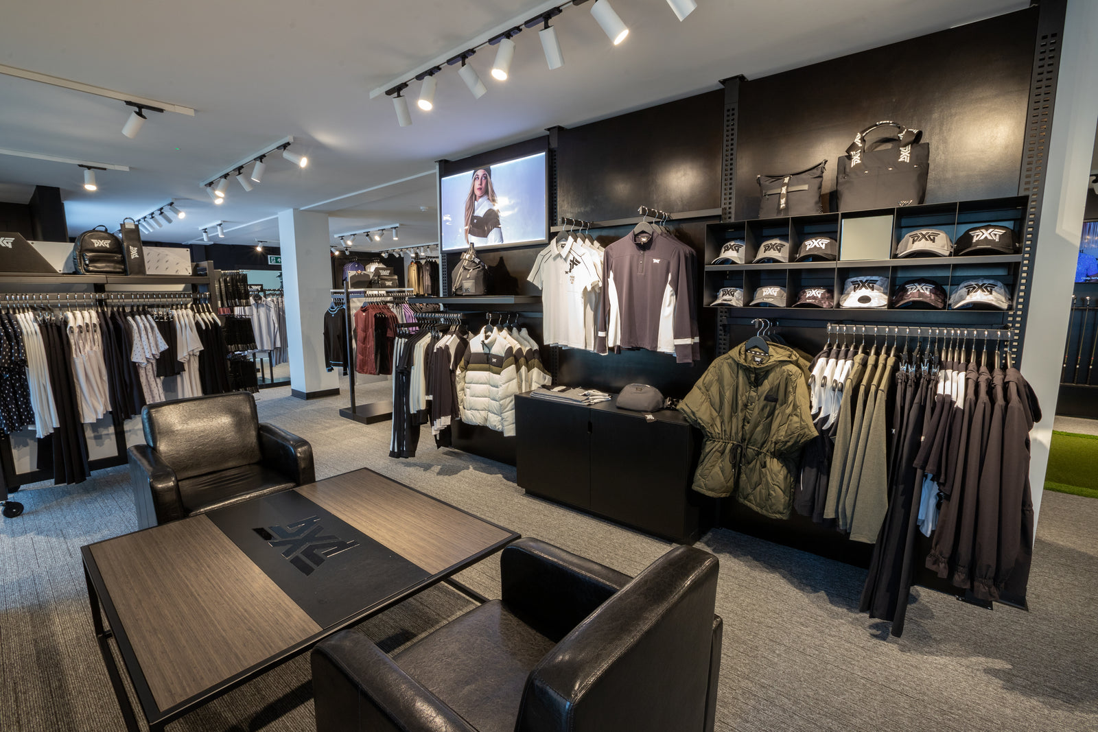 Modern clothing store interior with racks of clothes and a seated area.