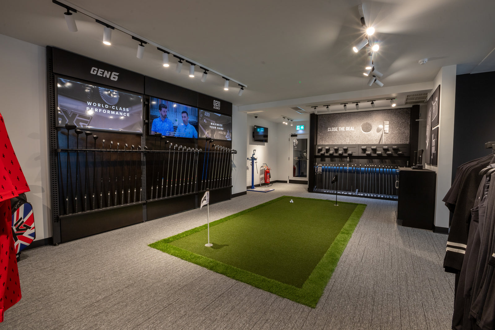 Putting green turf area and multiple screens displaying golf-related content.