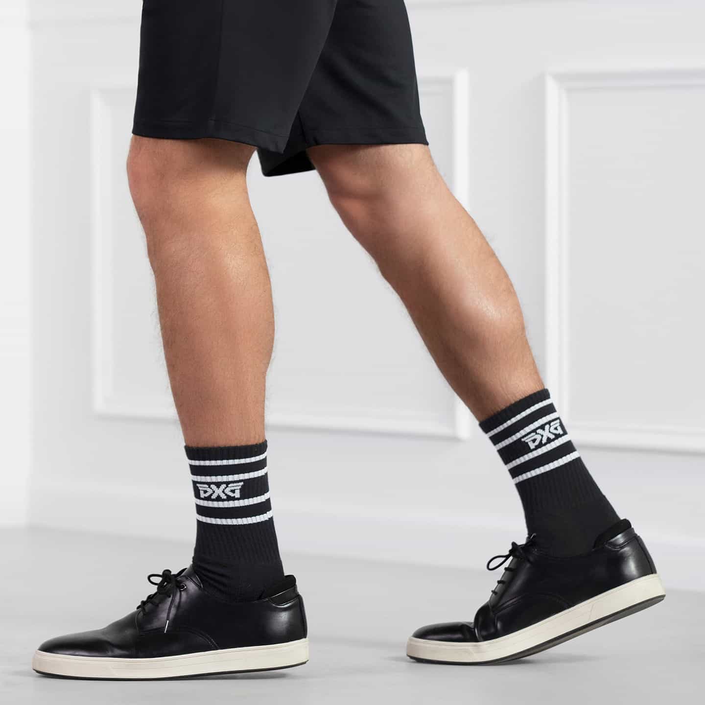 PXG black men's stripe crew socks with a white stripes on a white background