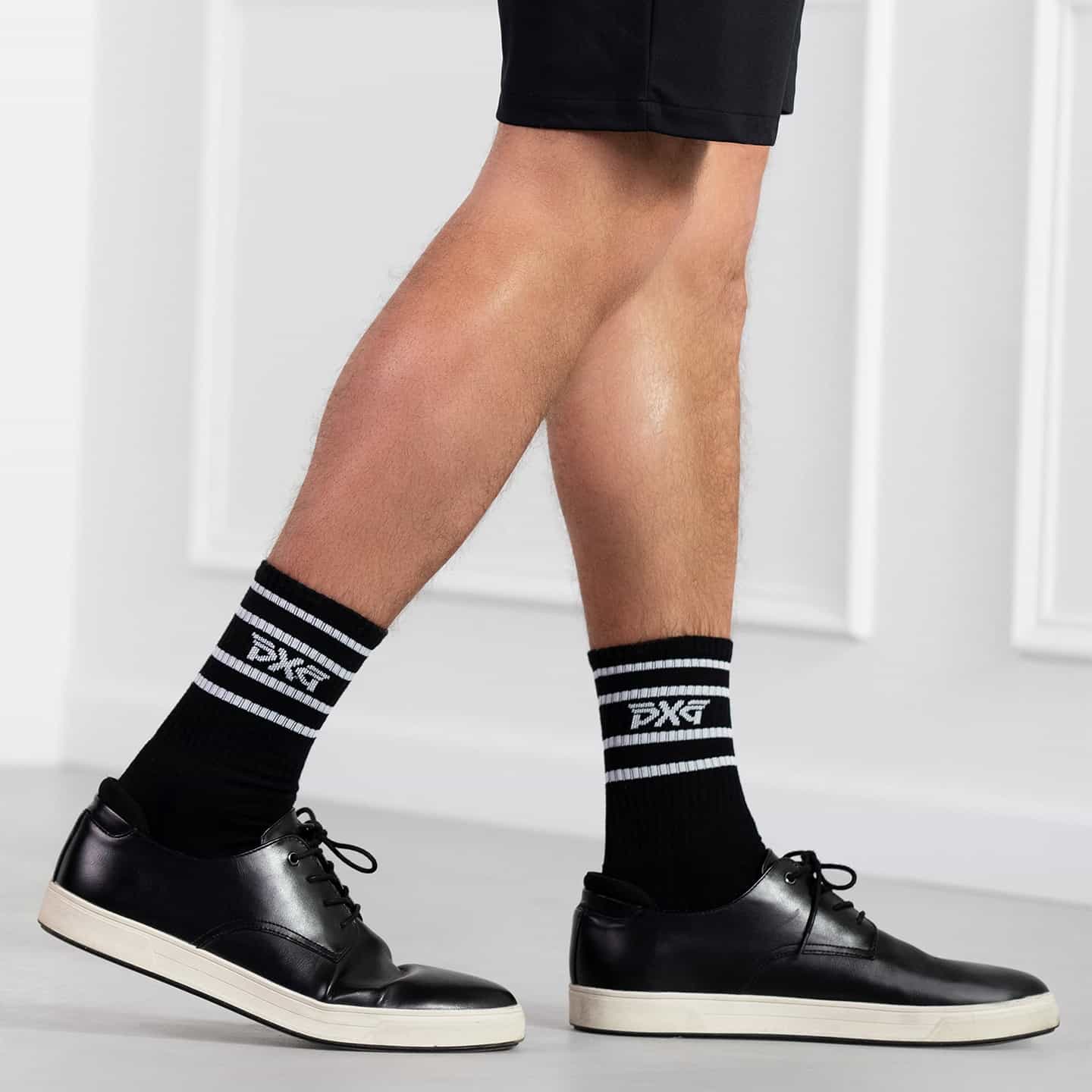PXG black men's stripe crew socks with a white stripes on a white background