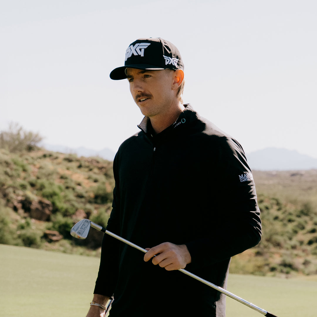 PGA Tour Pro Jake Knapp wearing a PXG Golf Hat on a golf course and holding a PXG Golf Club.