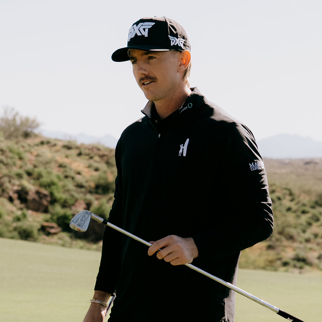 PGA Tour Pro Jake Knapp wearing a PXG Golf Hat on a golf course and holding a PXG Golf Club.