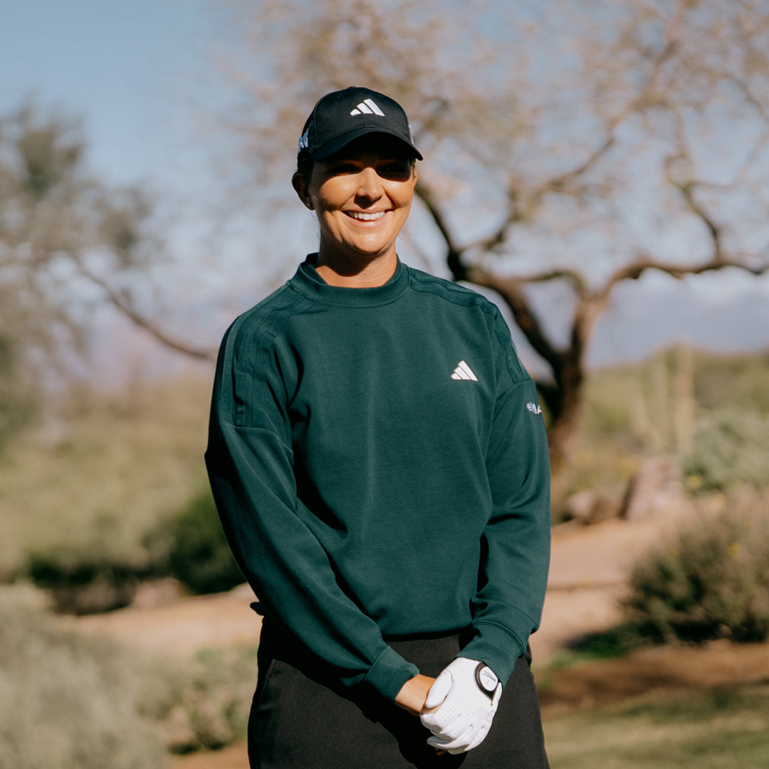 LPGA Tour Pro Linnea Strom wearing a Golf Hat on a golf course and smiling.