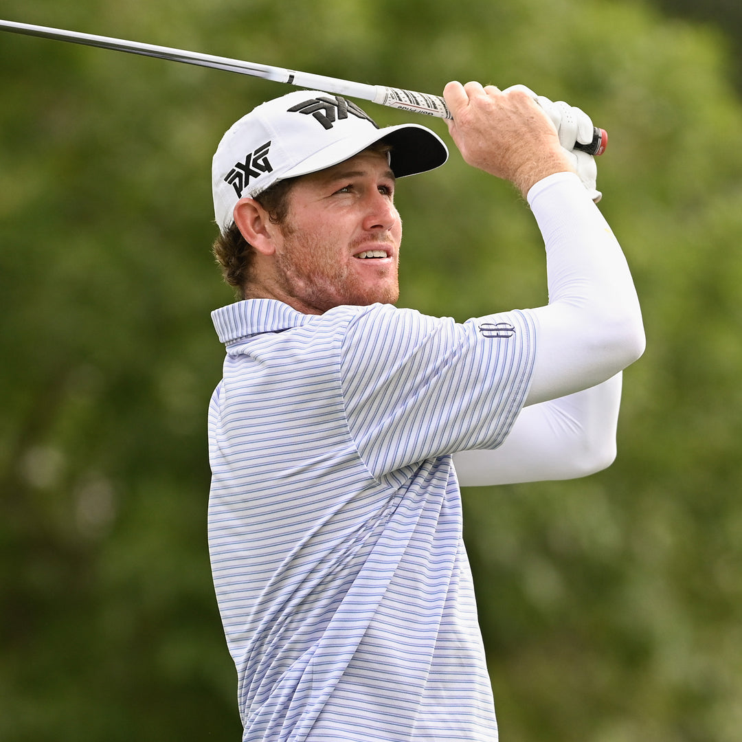Pro Patrick Cover wearing a PXG Hat and swinging a golf club on a golf course.