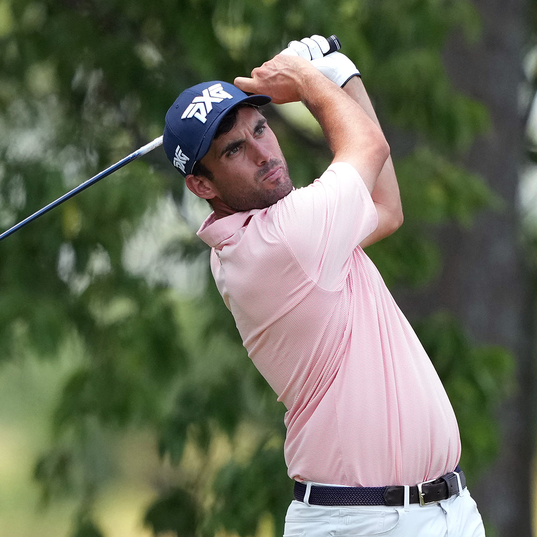 Pro Ryan McCormick wearing a PXG Hat and swinging a golf club on a golf course.